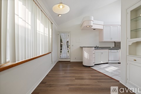A kitchen with white cabinets and a wooden floor.