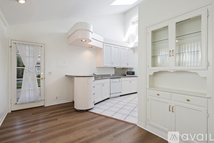 A kitchen with white cabinets and a wooden floor.