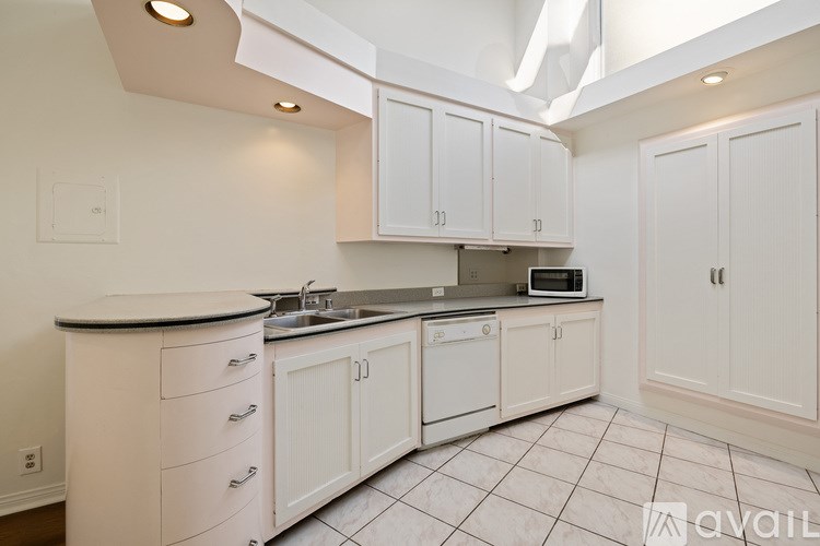 A kitchen with white cabinets and a black countertop.