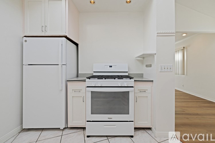 A white kitchen with a fridge, stove, and oven.