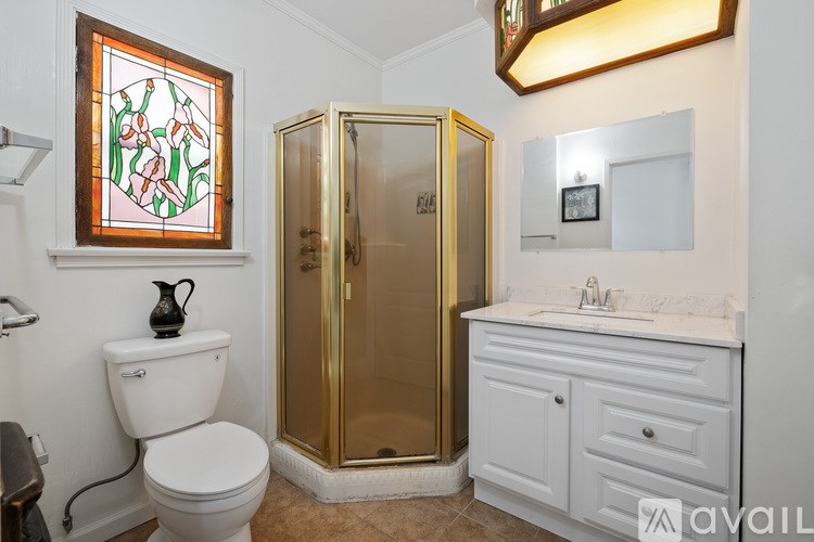 A bathroom with a toilet, sink, and a stained glass window.