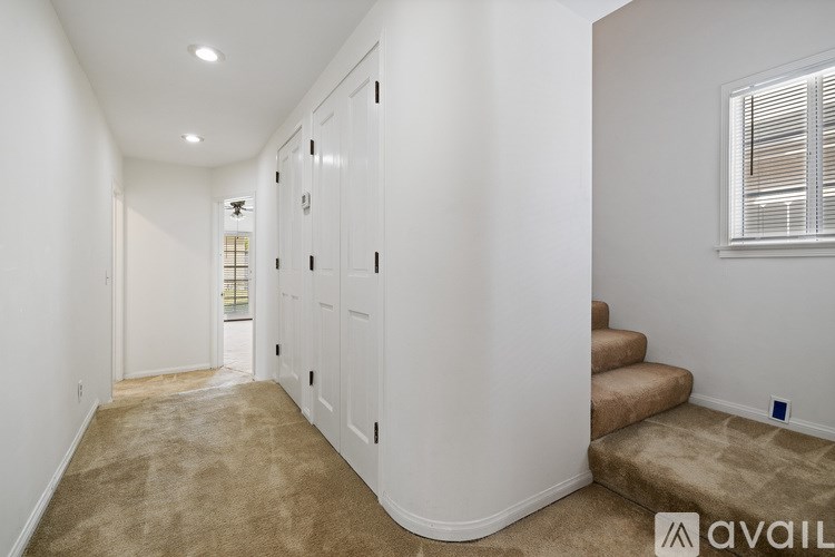 A hallway with white walls and a carpeted floor.
