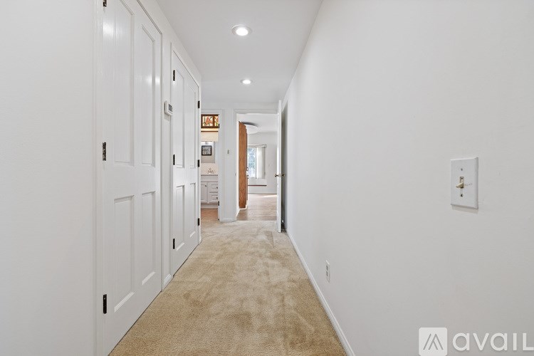 A long hallway with white walls and carpeted floor.