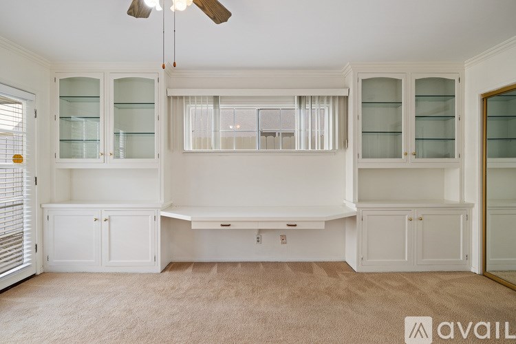 A spacious room with a long white table and white cabinets with glass doors.
