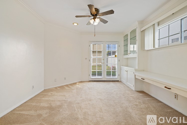 A room with a carpeted floor and a ceiling fan.