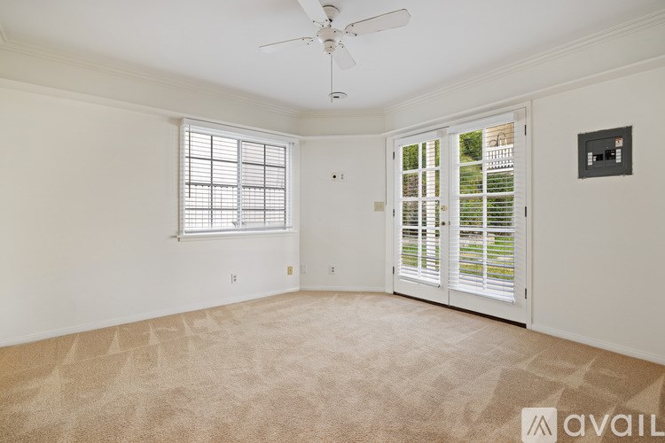 A room with a carpeted floor, a ceiling fan, and a window with blinds.