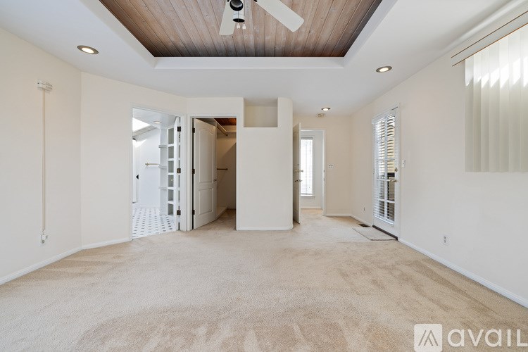 A spacious room with a ceiling fan and a carpeted floor.