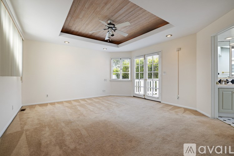 A spacious room with a ceiling fan and carpeted floor.