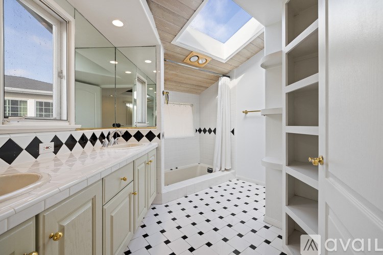 A bathroom with a skylight and a black and white floor.