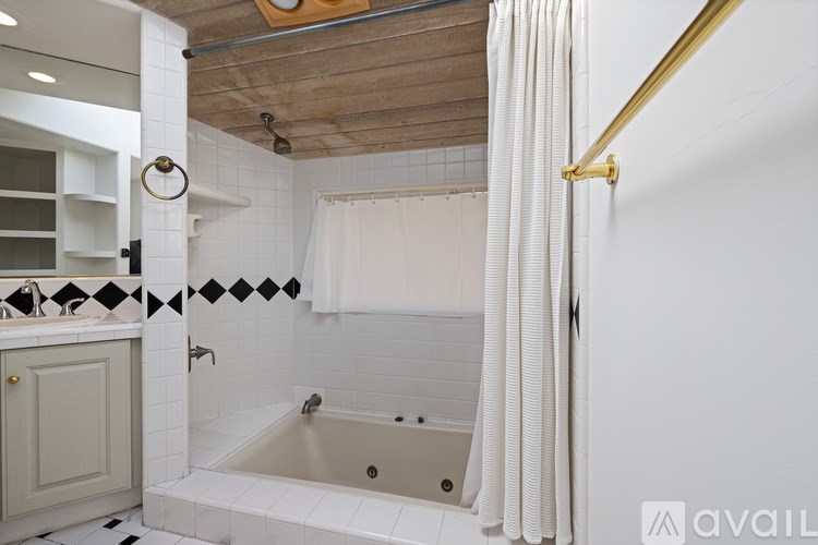 A bathroom with a white tub and a white shower curtain.