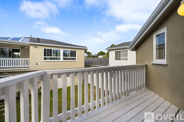 A balcony with a white railing and a wooden floor.