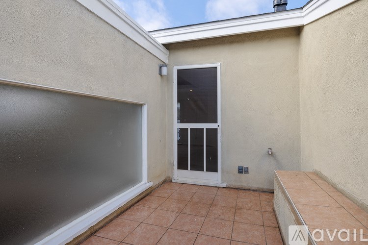 A balcony with a glass door and a tiled floor.