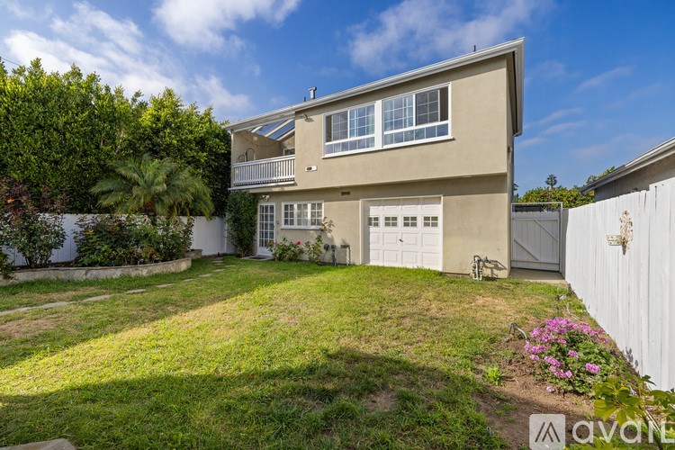 A two-story house with a white fence and a green lawn.
