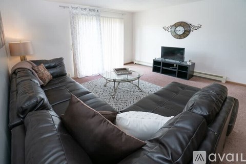 A living room with a black leather couch and a glass coffee table.