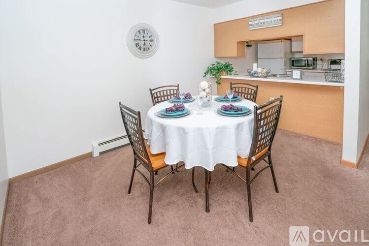 A dining room with a round wall clock and a dining table set for four.