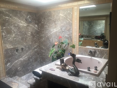 A bathroom with a marble wall and a pink tub.