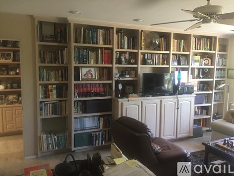 A living room with a large bookshelf filled with books and a flat screen TV on a cabinet.