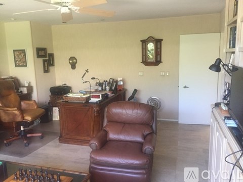 A living room with a brown leather chair and a wooden cabinet.