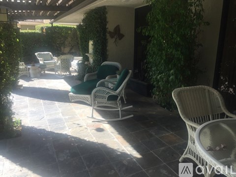 A patio with chairs and a table is covered in sunlight.