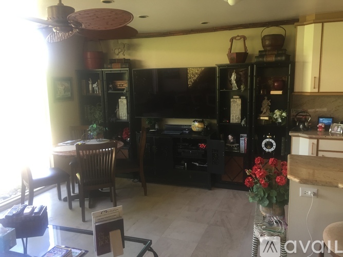 A living room with a dining table and chairs, a television, and a cabinet with glass doors.