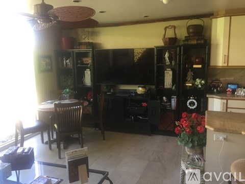 A living room with a dining table and chairs, a television, and a cabinet with glass doors.
