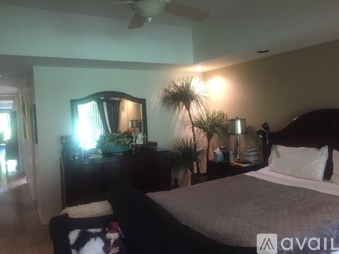 A bedroom with a bed, dresser, and a ceiling fan.