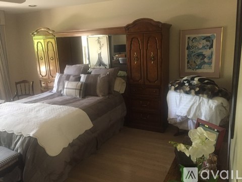 A bedroom with a large bed and a wooden cabinet.
