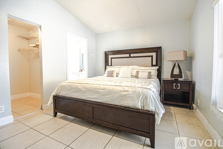 A bedroom with a large bed and a nightstand with a lamp.
