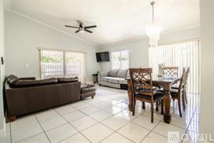 A living room with a brown couch, a wooden dining table, and a ceiling fan.