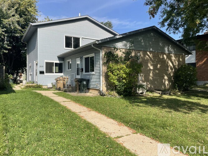 A house with a grey siding and a brown roof with a small front yard.