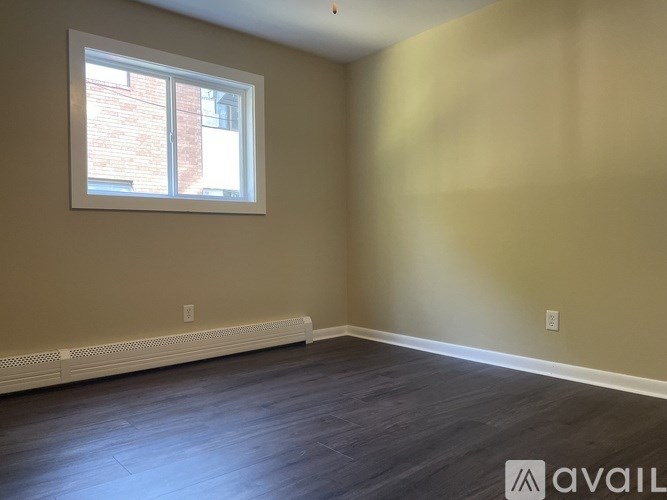 A room with a window and a wooden floor.