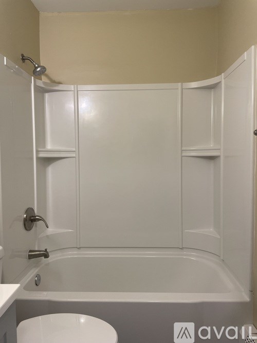 A white bathroom with a tub and towel rack.