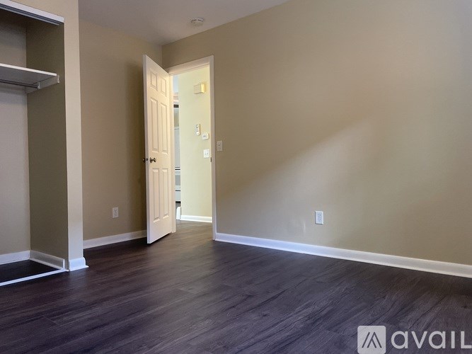 A room with a wooden floor and a doorway leading to another room.