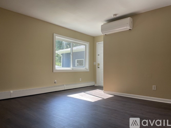 A room with a window, a door, and a wall-mounted air conditioner.