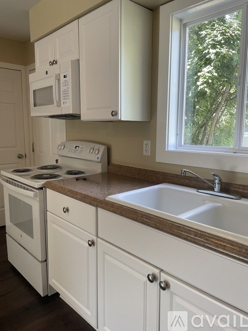 A kitchen with white cabinets and a window.
