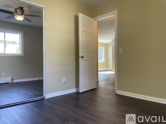 A room with a ceiling fan and a door leading to another room.