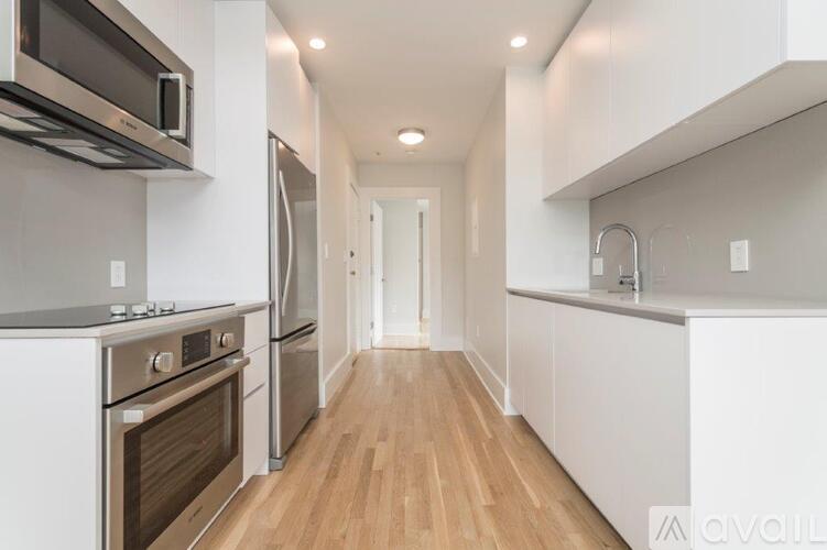 A modern kitchen with stainless steel appliances and wooden floors.