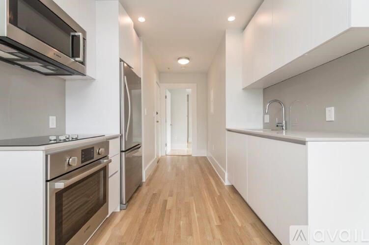 A modern kitchen with stainless steel appliances and wooden floors.