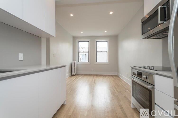 A kitchen with white cabinets and a wooden floor.