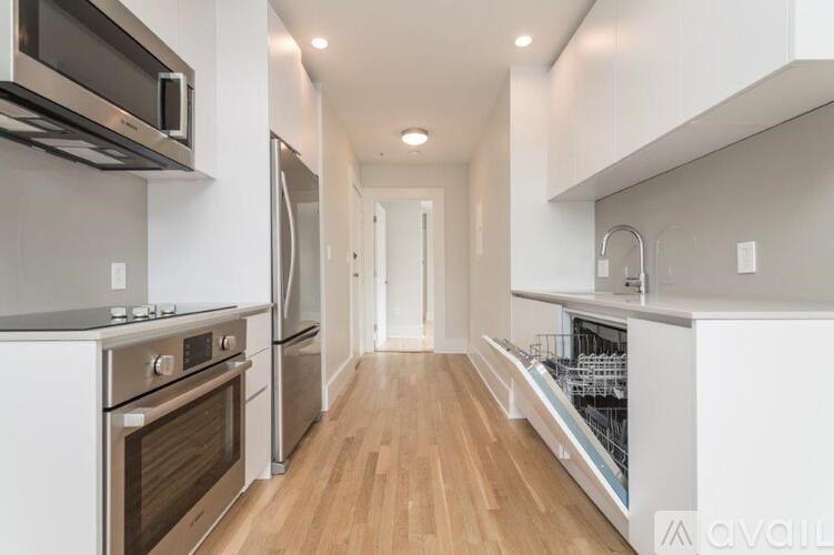 A modern kitchen with stainless steel appliances and wooden floors.