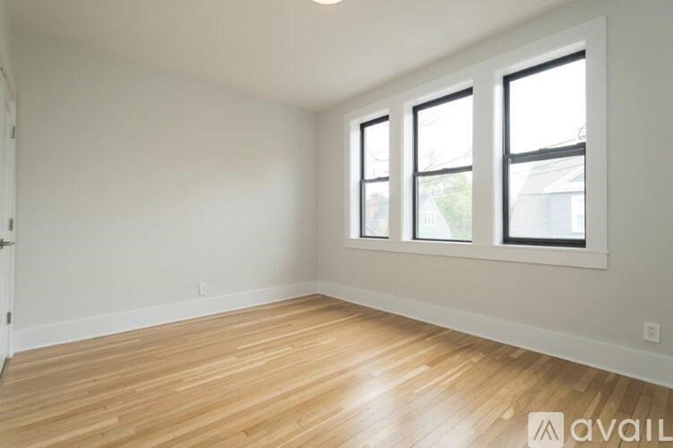 A room with wooden flooring and three windows.