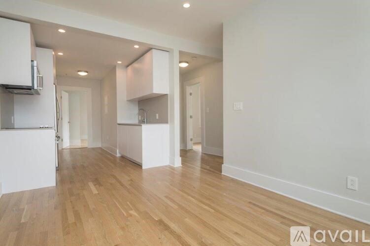 A spacious kitchen with wooden floors and white walls.
