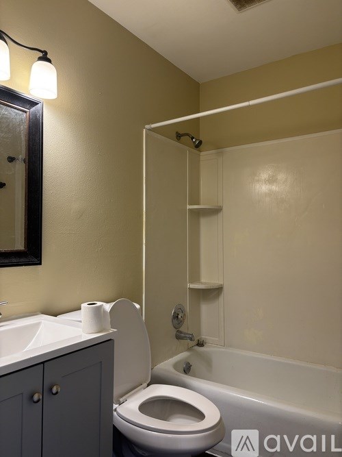 A bathroom with a toilet, sink, and mirror.