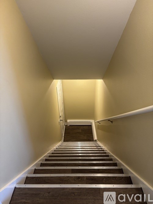 A staircase with a carpeted floor and wooden steps leading to a door at the end.