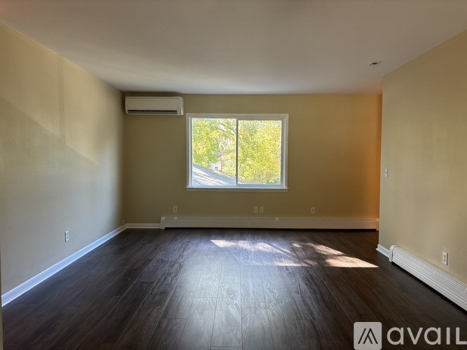 A spacious room with wooden flooring and a window.