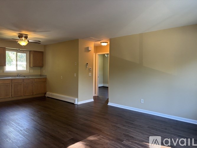 A spacious room with wooden floors and a ceiling fan.
