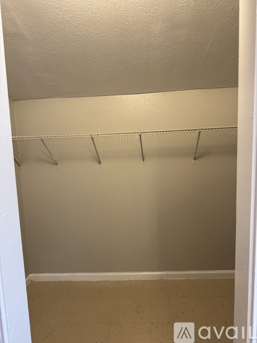 A small, empty closet with a shelf and a white door.