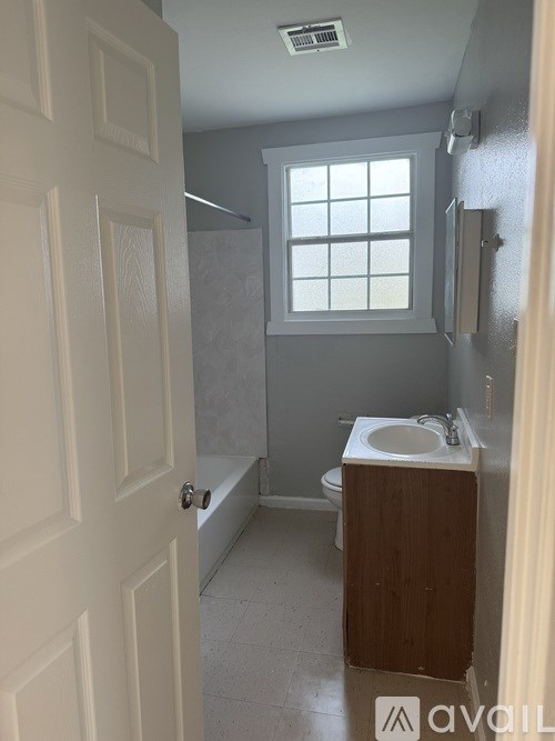 A bathroom with a toilet, sink, and window.