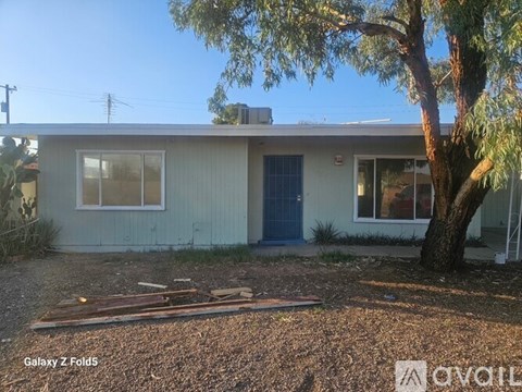 A house with a blue door and a tree in front.