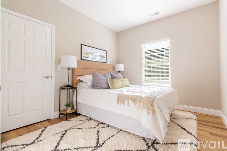 A bedroom with a bed, two lamps, and a picture on the wall.